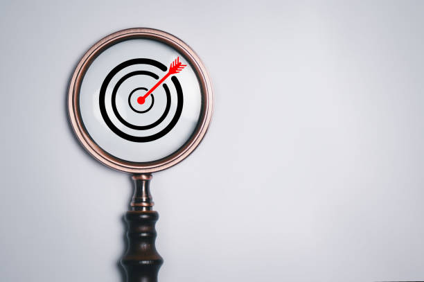 Target board inside of vintage magnifier glass for focus business objective on white background and copy space.