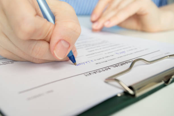 istock Financial affidavit, hand fills out a document, accounting statement, analysis. 2152751535