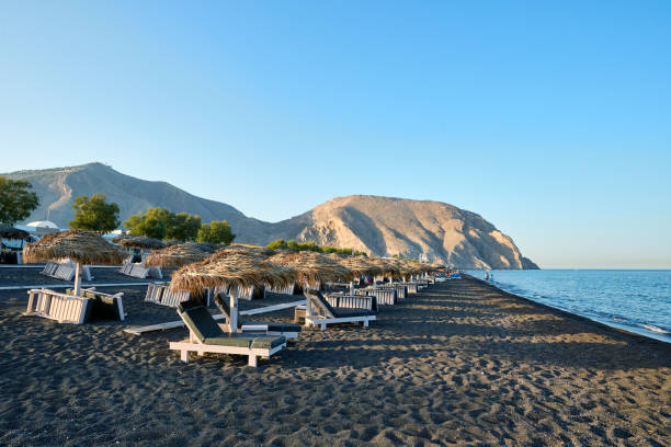Perivolos Beach, Santorini, Greece Straw parasols and sun beds on the beach at Perivolos with black sand and small dark pebbles, located in the southern part of the island of Santorini. Greek Islands, Santorini, European Vacation. santorin stock pictures, royalty-free photos & images