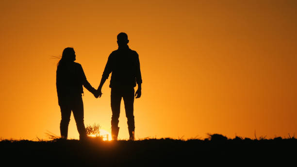 istock Young couple admiring the sunset over a field 2152758012