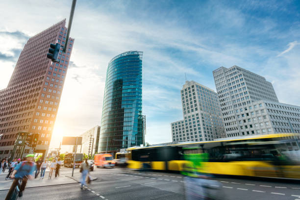A vibrant cityscape of Berlin showcasing modern architecture and busy street life with pedestrians and moving buses under a clear sky.
