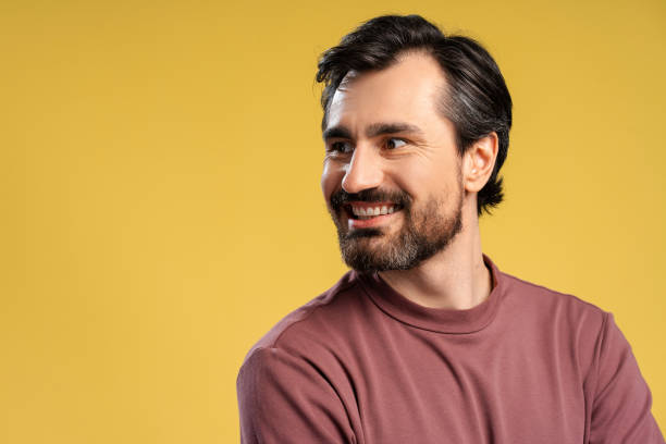 istock Happy bearded young man posing in studio looking to the side. Isolated on yellow 2152760609