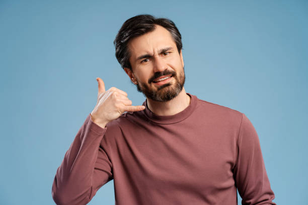 istock Young man doing phone finger gesture like call posing in studio looking at camera 2152760615