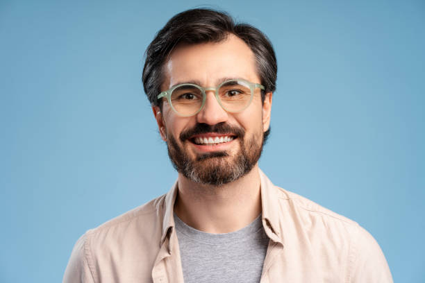 istock Happy young man in glasses posing in studio, looking at camera. Isolated on blue background 2152761656