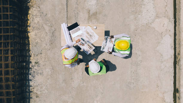 istock High angle view of international architect, engineer looking at blueprints at industrial factory Heavy industrial production plants. 2152768463