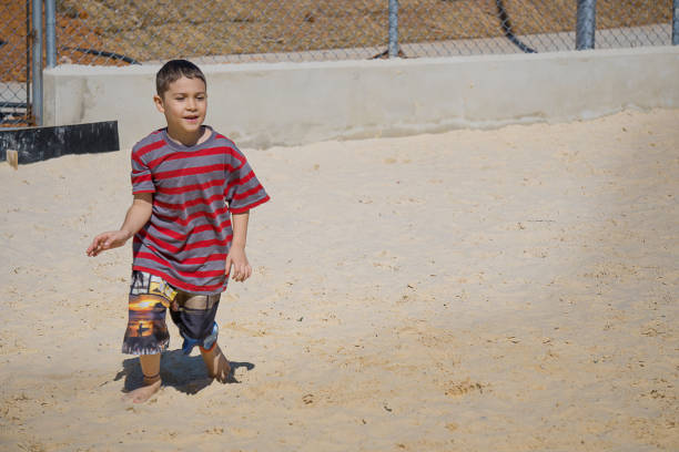 Boy playing in the sand of a public park in the city. The photo was taken on a very sunny day in the city of Sorocaba, State of São Paulo in Brazil.