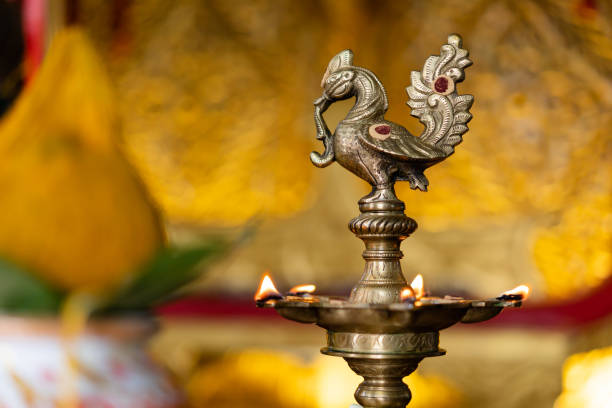 Peacock design diya oil lamp (Kuthu Vilakku) set against a blurred backdrop.