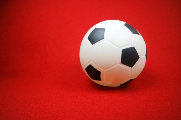 istock a small white and black toy rubber ball. Red background 2152779811