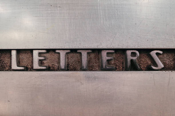 Word letters is  cast etched into a steel surface of an old mail box, which is weathered and scratched over many decades of use.