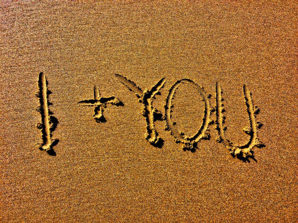 The image displays I + YOU deeply etched into a sandy surface.
