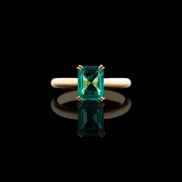 istock Beautiful yellow gold ring with diamonds and emerald on a black background 2152788487