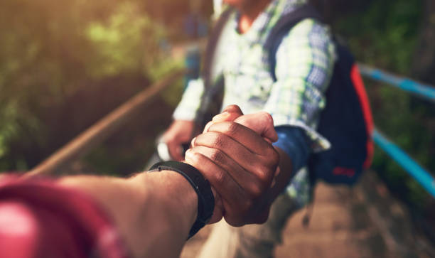 People, pov and holding hands for mountain hike or friends support for exercise challenge, trekking or fitness. Athlete, stairs and together in nature forest for cardio adventure, tourism or travel