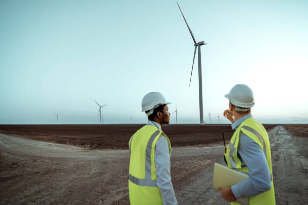 istock Rear view of two engineers talking on a filed with windmills at the background 2152803038