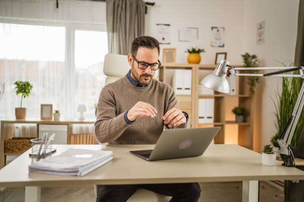 istock One adult man sit at office and look, read document on laptop at office 2152803725