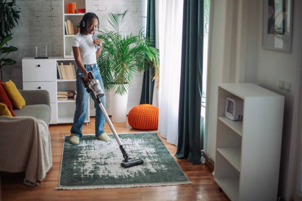 istock Woman using wireless vacuum cleaner in her apartment 2152805150