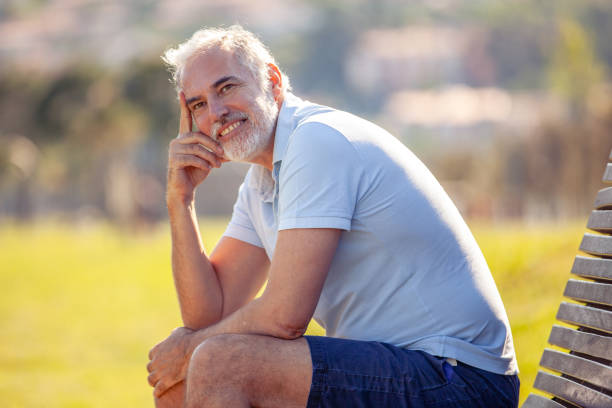 istock Smiling middle age man portrait sitting on bench outdoors and looking at view 2152814598