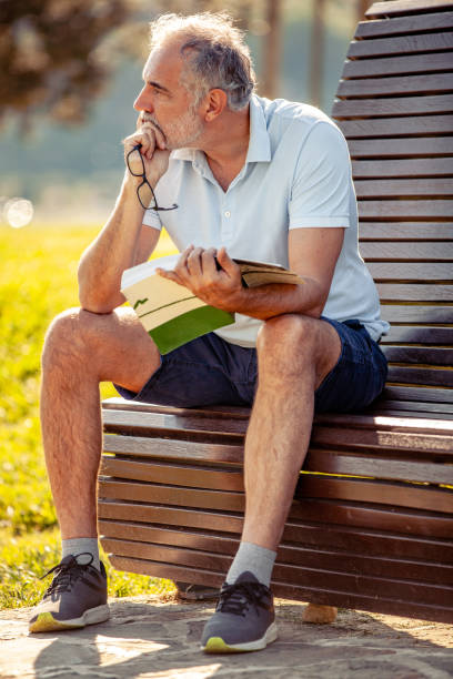 istock A pensive Middle-aged man reading a book in the public park 2152814629