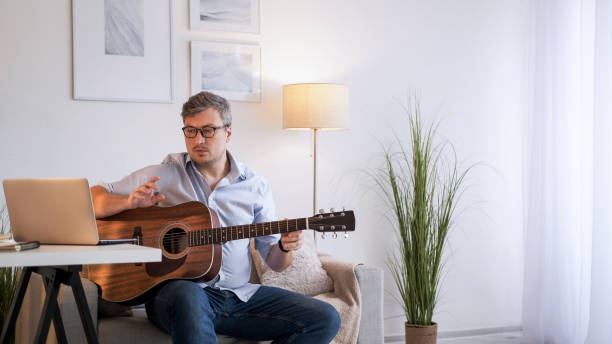 istock Guitar video lesson music tutor man laptop home 2152815140