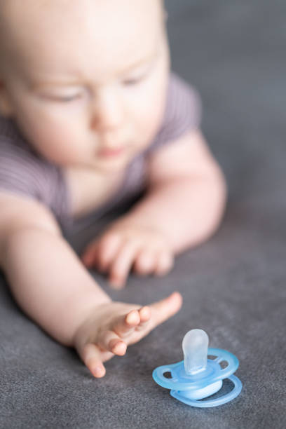 istock Baby stretching to reach the blue pacifier. Selective focus. 2152820322
