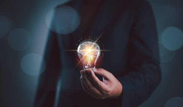 istock Businessman holding illuminated lightbulb, idea, innovation and inspiration with glowing virtual brain, smart intelligent creativity with bulbs, Motivation and innovation concept 2152824107