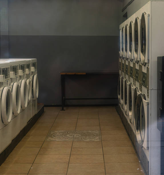 Modern electronic washing machine with old vacuum cleaner in front of a wall with retro wallpaper