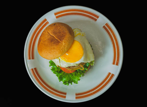 A juicy homemade hamburger patty topped with a sunny side up fried egg. The burger is on a white plate.