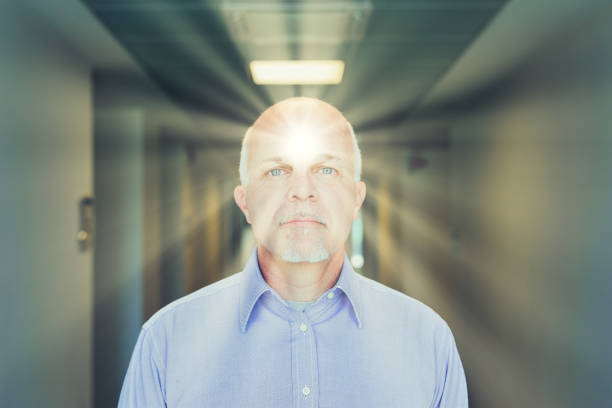 Elderly man glows from within, light casting forward from his presence in a corridor, exuding vitality and focus