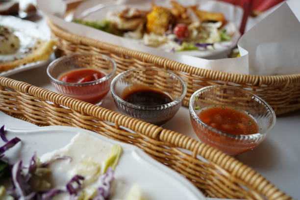 Restaurant food in a wicker basket with sauces on the table