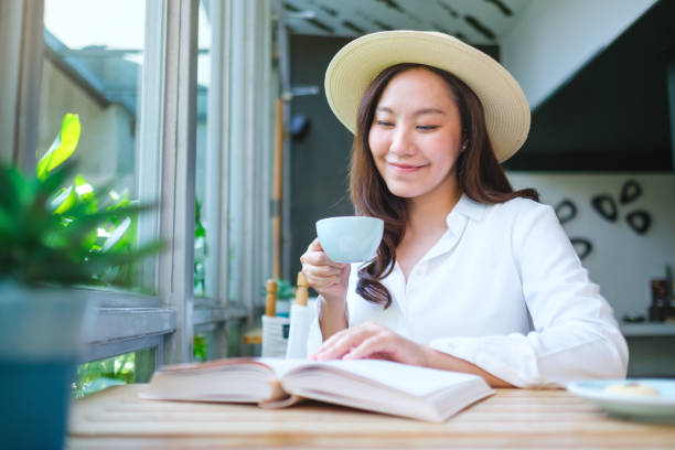 istock Portrait image of a beautiful young woman with hat drinking coffee while reading book 2152834761
