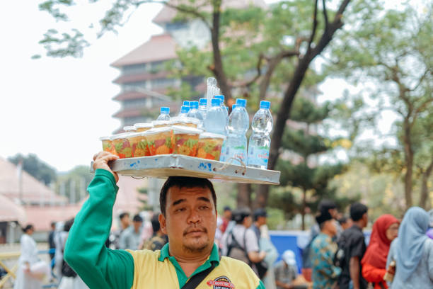 Jakarta, Indonesia- march, 29, 2024 : Drink seller is carrying his wares on his head