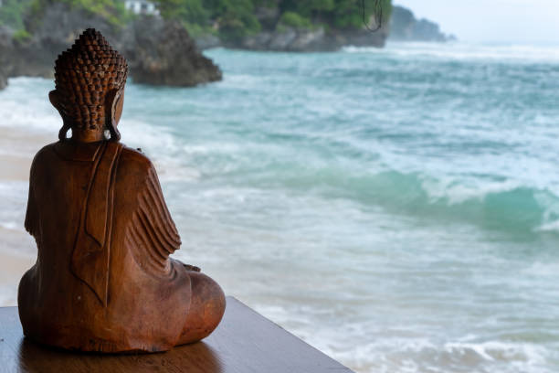 Retreat concept, view on Bingin beach, wooden Buddha from back, meditation looking at waves and ocean