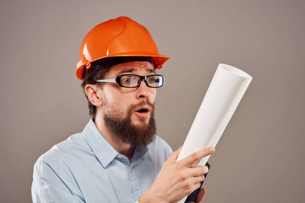 istock Male engineer with glasses in orange paint. Professional blueprints in hands 2152840967