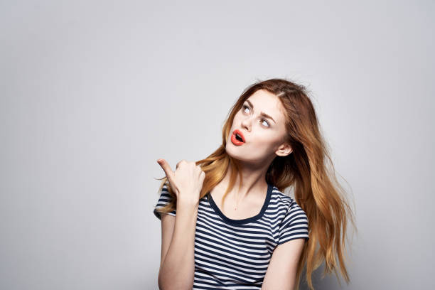 cheerful woman in a striped t-shirt gesture with his hands model studio. High quality photo