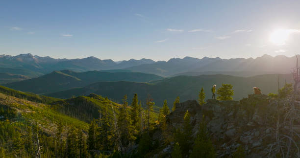 Senior couple explore mountain top together above valley and distant mountain range at sunrise