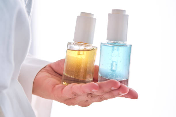 istock Two yellow and blue serums in a womans hands in a robe. 2152846367