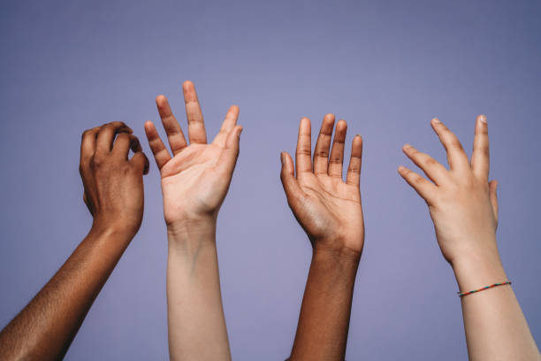 Four hands up against a purple background