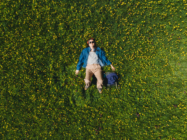 istock A woman is lying down on the grass surrounded by yellow flowers 2152852826