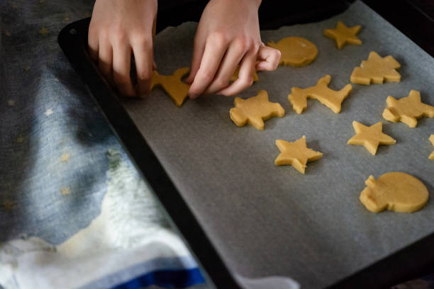 istock Girl puts gingerbread cookies on a baking tray 2152853426
