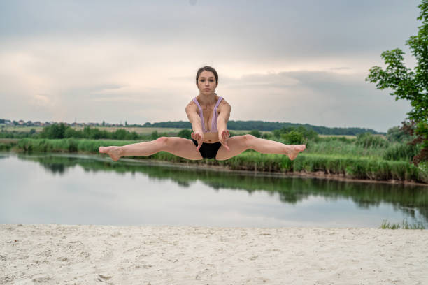 a fitness instructor shows how to correctly perform stretching exercises on the sandy shore of the lake. Workout at nature