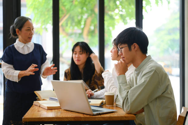 College students attentively listening to mature professor in the classroom College students attentively listening to mature professor in the classroom. research stock pictures, royalty-free photos & images