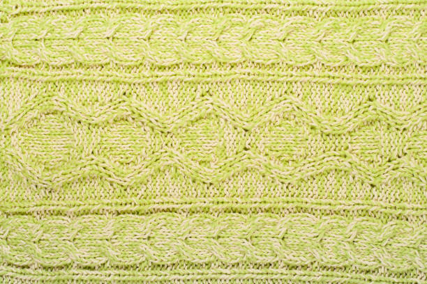 Sweater or scarf fabric texture large knitting. Knitted jersey background with a relief pattern. Braids in knitting . Wool hand- machine, handmade.