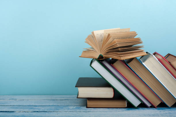 istock Book stacking. Open book, hardback books on wooden table and blue background. Back to school. Copy space for text. 2152861603