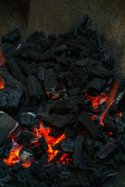 Coals with sparks in a huge old metal grill background