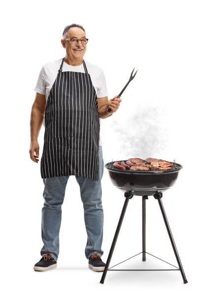 istock Mature man next to a portable barbecue grill holding a fork 2152863577