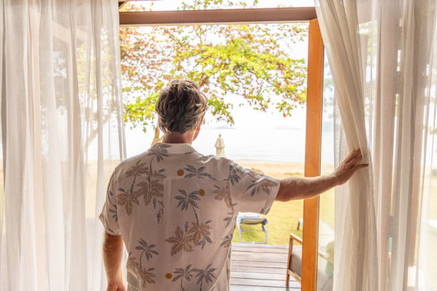istock Man On Vacation Standing at Doorway to a Beach View 2152869001