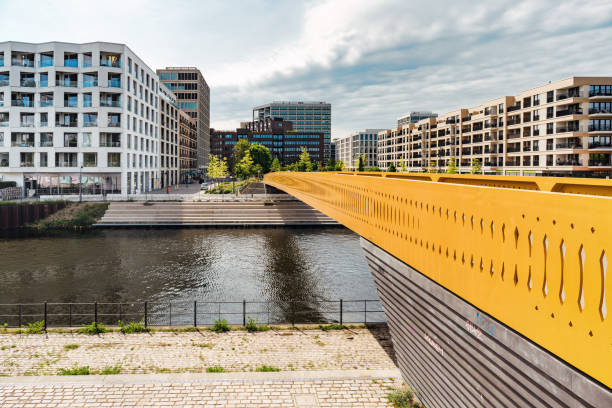 modern residential houses at river in central berlin , new district under construction with cranes in background