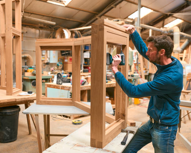 istock Carpenter In Workshop Using Drill To Attach Piece Of Wood To Window Frame 2152882357