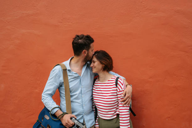 Portrait of a mid adult heterosexual couple against the deep orange wall