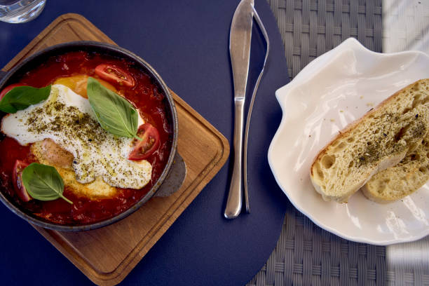 medium sized woman in peach color dress eating Shakshouka in modern restaurant