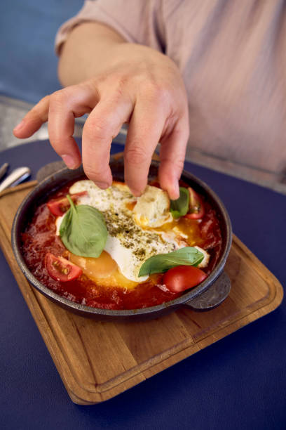 medium sized woman in peach color dress eating Shakshouka in modern restaurant